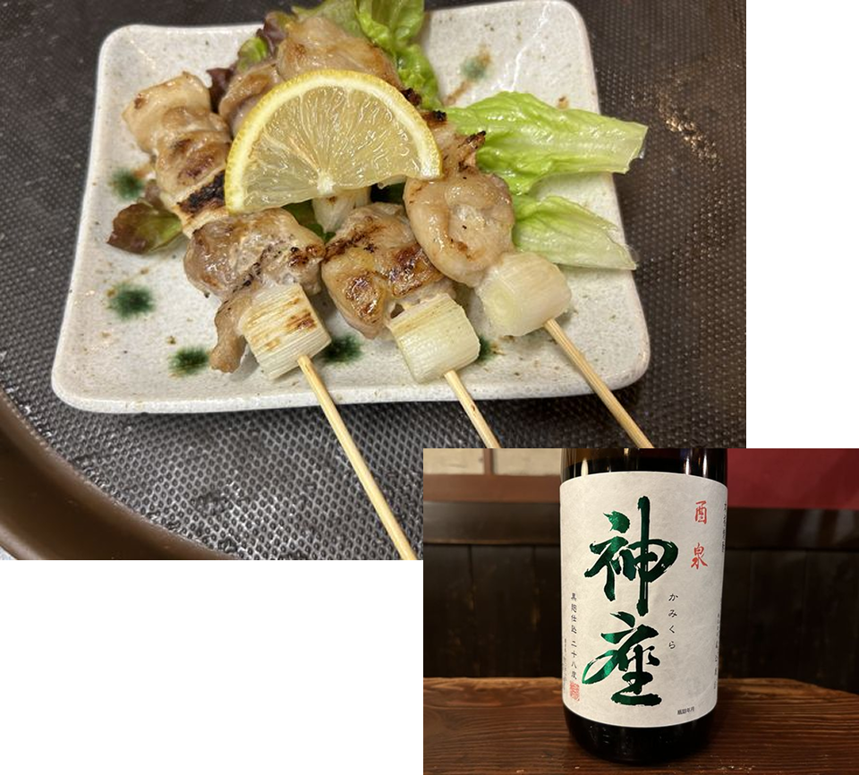 レモンが添えられた焼き鳥と「神座」という銘柄の焼酎ボトル